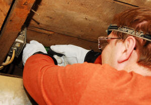Jonathan Murphy of Hot & Cold Electric takes apart a junction box in a basement during a job rewiring bathroom switches, outlets, and light.
